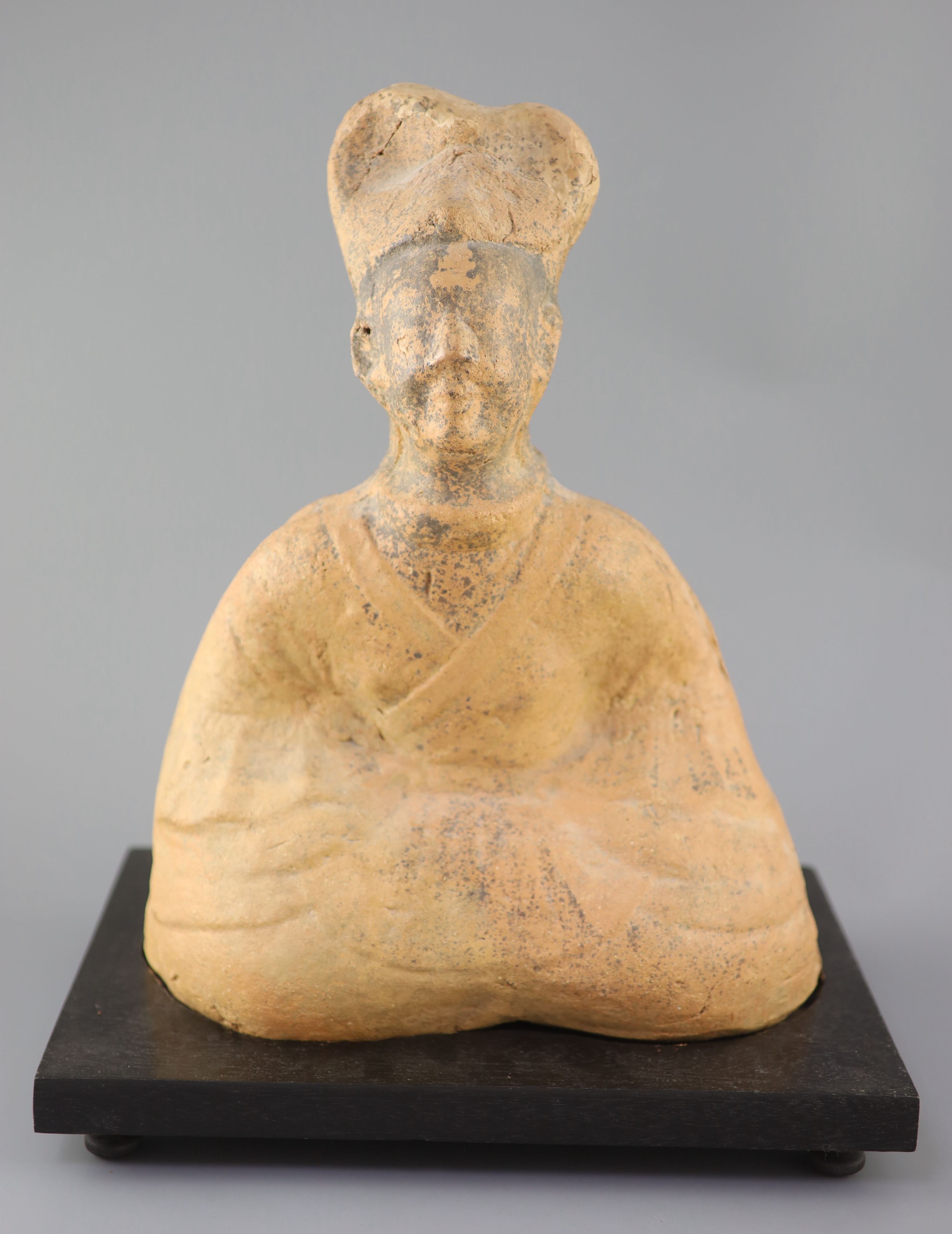 A Chinese pottery figure of a seated official, Tang dynasty or later 41cm high, wood stand